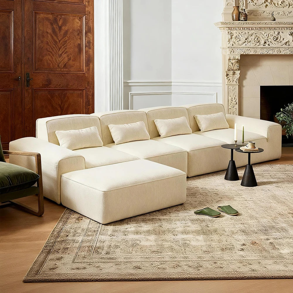 Beige sectional boneless sofa in a living room with a fireplace and wooden door.